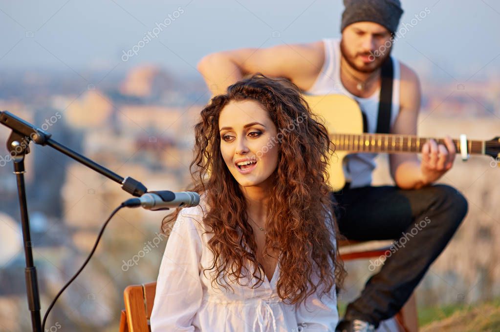 Country-Sängerin mit Gitarre auf einem Feld bei Sonnenuntergang