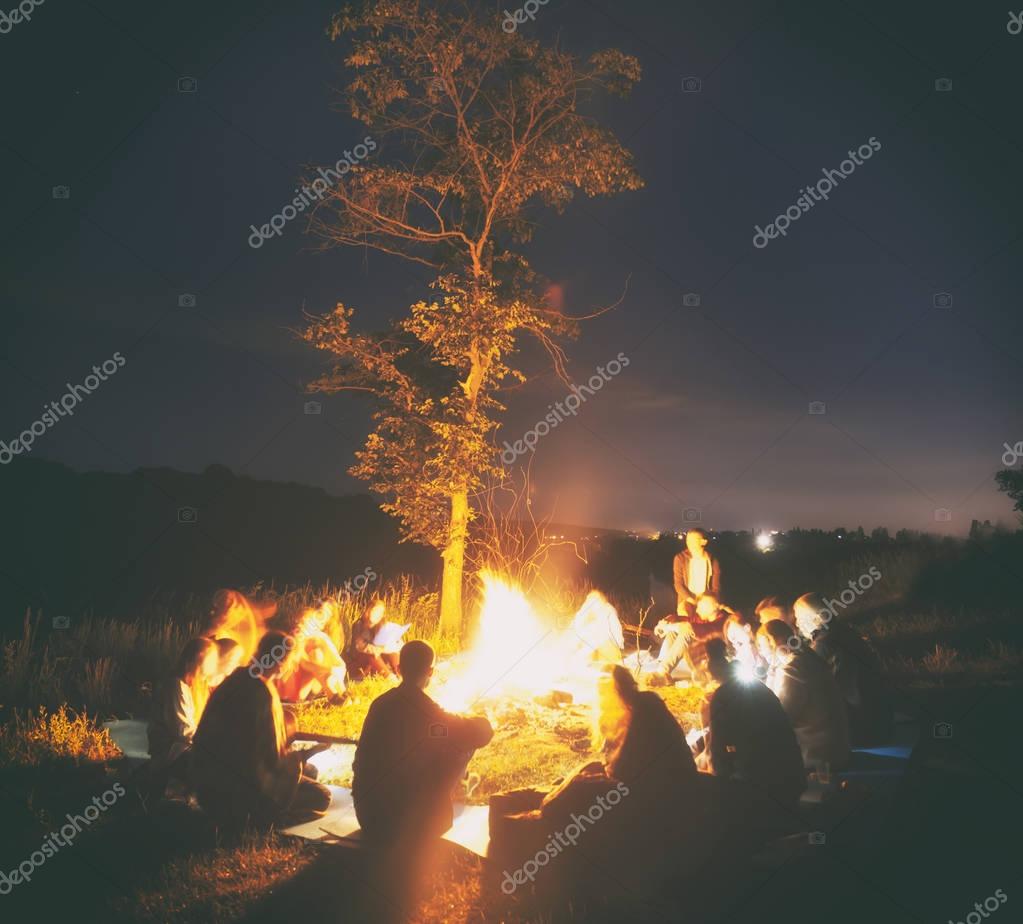 Gruppe sitzt am Lagerfeuer und spielt Gitarre bei einem Community-Wochenende